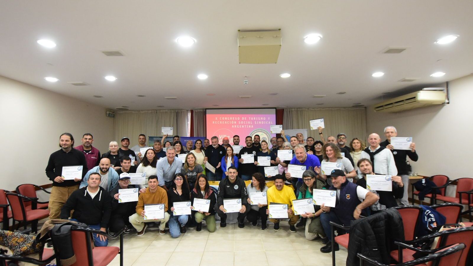 Representantes sindicales y participantes del X Congreso de Turismo Social y Sindical posan con certificados en Villa Gesell